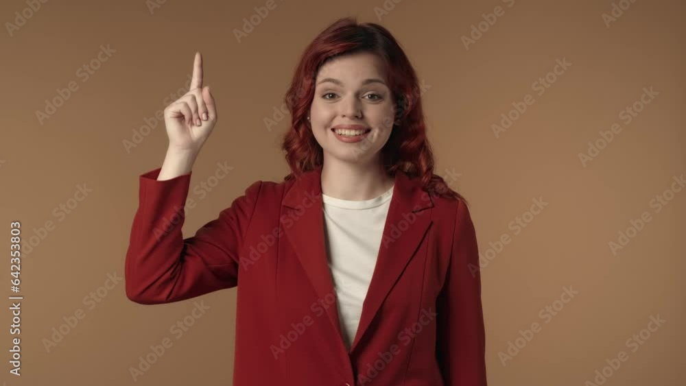 Medium isolated video of an astonished, happy and active young woman pointing her finger up to highlight something above her. Medium isolated video of an astonished, happy and active young woman pointing her finger up to highlight something above her.