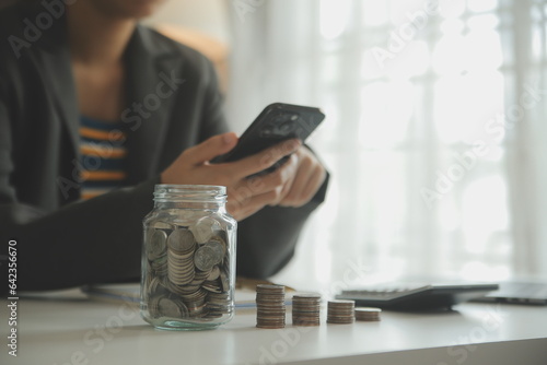 saving money and accounting concept. business man putting coin insert to jar and make acounting book for finance management to investment and saving. photo