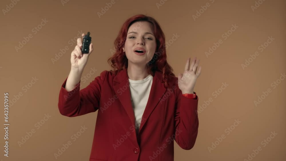 Medium isolated video of an astonished, happy and active young woman holding a car key in her hand and expressing pure joy about the purchase. Medium isolated video of an astonished, happy and active young woman holding a car key in her hand and expressing pure joy about the purchase.