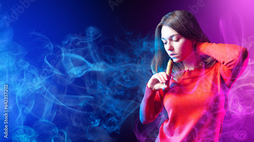 Woman smokes vape. Girl in clouds of smoke. Young lady vaper. Beautiful woman with electronic cigarette. Student with vape device. Female is standing in puff of smoke. Steam smoking. Vape hobby