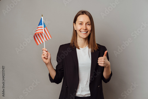 Studio portrait of a young smiling woman holding USA flag and a thumb up. photo