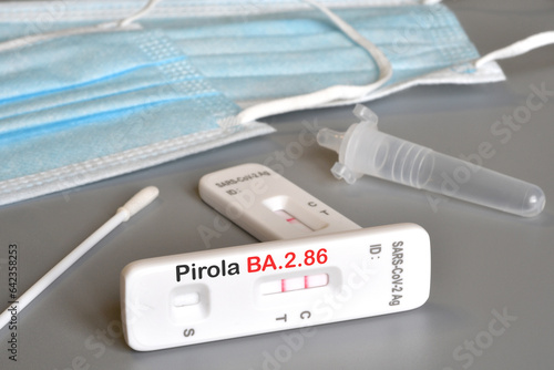 SARS‑CoV‑2 antigen test kit for self testing with positive result with text Pirola BA.2.86 on grey background. Close-up. Concept for the new Covid 19 Pirola Variant photo