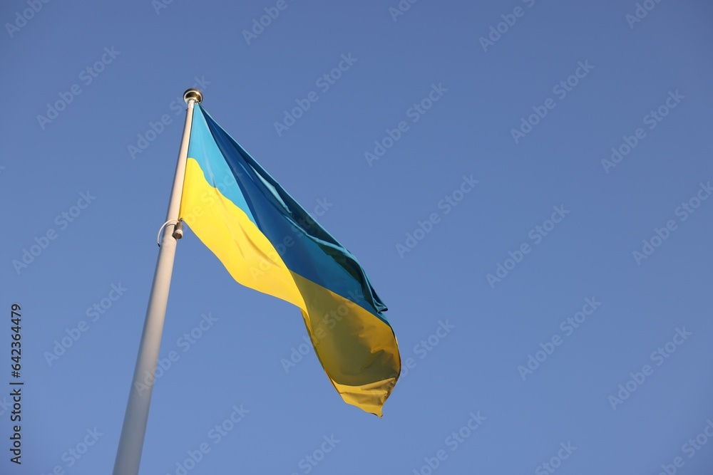 Flag of Ukraine fluttering against blue sky, low angle view. Space for text Flag of Ukraine fluttering against blue sky, low angle view. Space for text