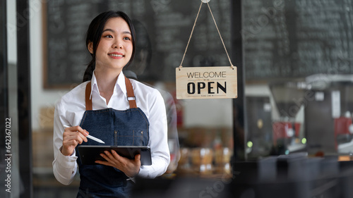 Startup successful small business owner sme beauty girl stand with tablet smartphone in coffee shop restaurant.