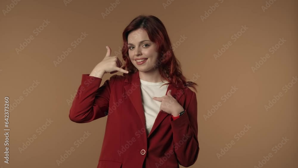 Medium isolated video of a satisfied, happy and active young woman pointing at the camera, then imitating a phone with her hand to offer calling the advertiser. Medium isolated video of a satisfied, happy and active young woman pointing at the camera, then imitating a phone with her hand to offer calling the advertiser.