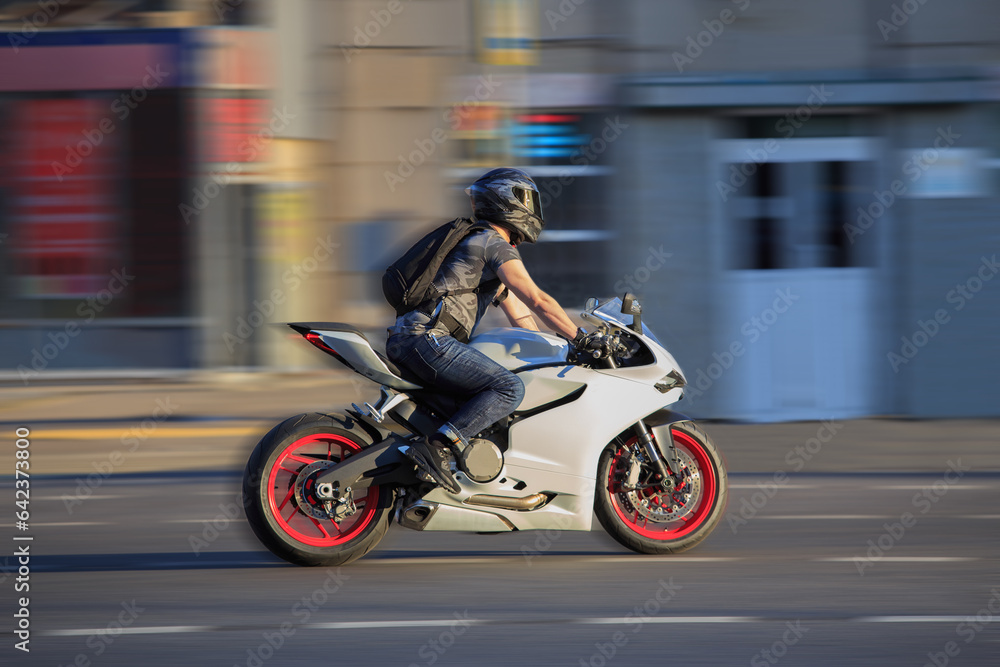Motorcyclist on motorcycle rides on city street