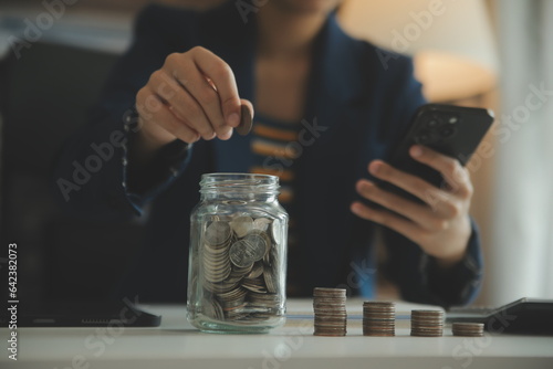 saving money and accounting concept. business man putting coin insert to jar and make acounting book for finance management to investment and saving. photo