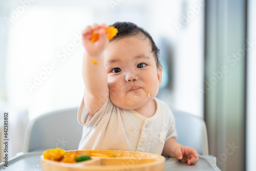 離乳食後期でをつかみ食べをしてご機嫌な生後9か月の赤ちゃん