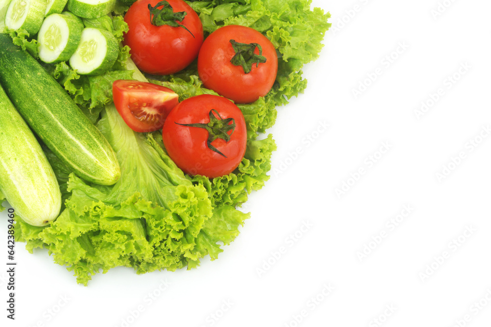 Cucumbers and tomatoes on salad leaves background isolated on white. Copy space for text.