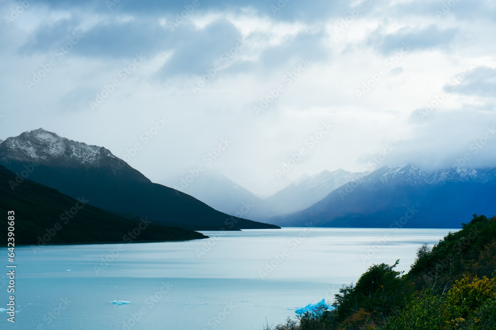 Snowy mountains near calm lake in cloudy day Snowy mountains near calm lake in cloudy day