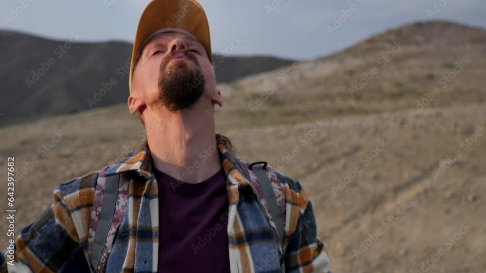 Portrait of a young adult handsome man in a cap and with a beard smoking a vape system pod in the early morning against the backdrop of a mountain landscape. Vape travel alternative to cigarettes Portrait of a young adult handsome man in a cap and with a beard smoking a vape system pod in the early morning against the backdrop of a mountain landscape. Vape travel alternative to cigarettes