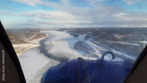Aerial shooting. view of the plane window. Beautiful winter landscape. Village with wooden houses. Dense coniferous forest. Heavy snowfall in Siberia.