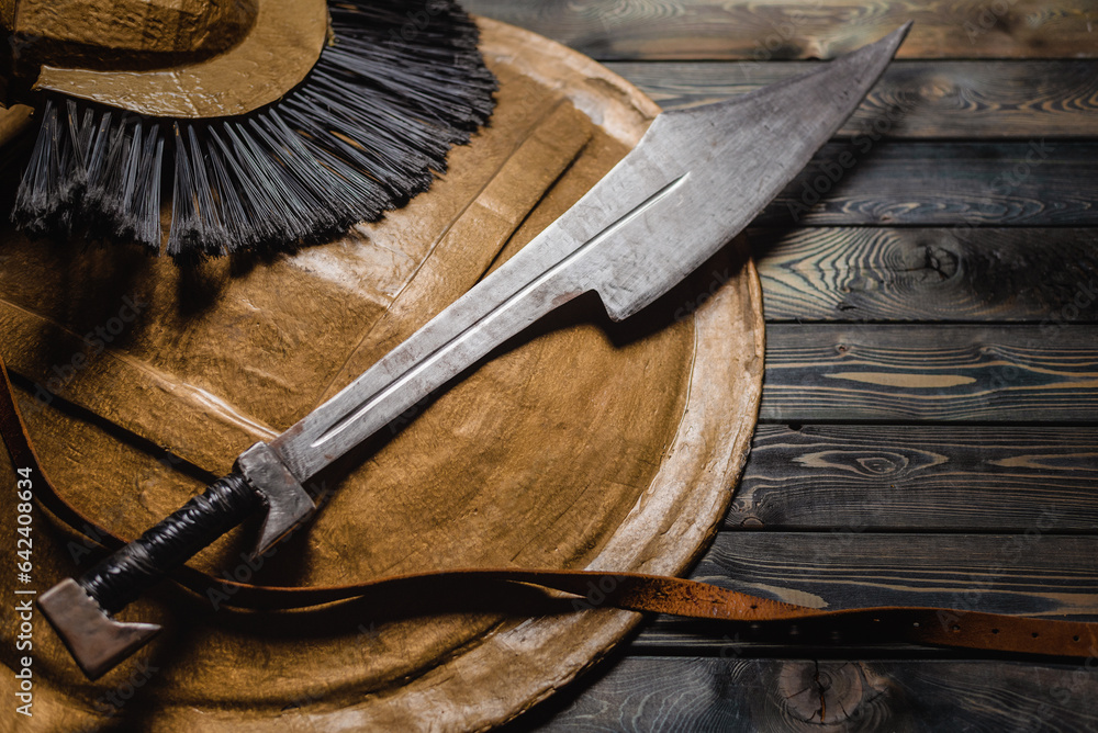 Ancient Spartan sword and shield on the wooden table background concept