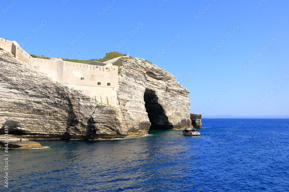 May 27 2023 - Bonifacio, Island of Corsica, France: boat in front of Grotto of Saint Antoine (Grotto of Napoleon) in Bonifacio