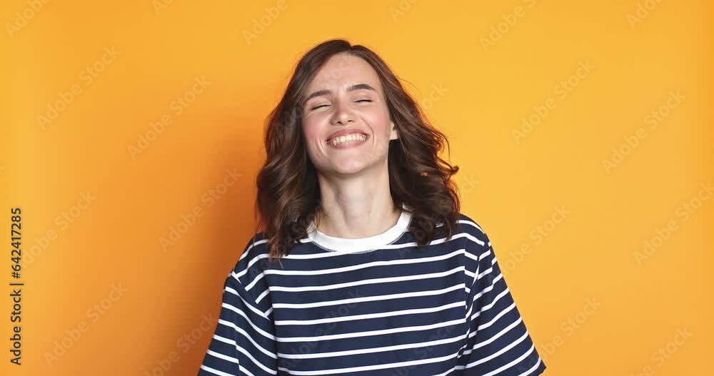 Overjoyed curly haired woman wins competition achieves goal and makes triumph gesture says yes feels like winner shows fist bump happy dream come true poses against yellow background. Overjoyed curly haired woman wins competition achieves goal and makes triumph gesture says yes feels like winner shows fist bump happy dream come true poses against yellow background.
