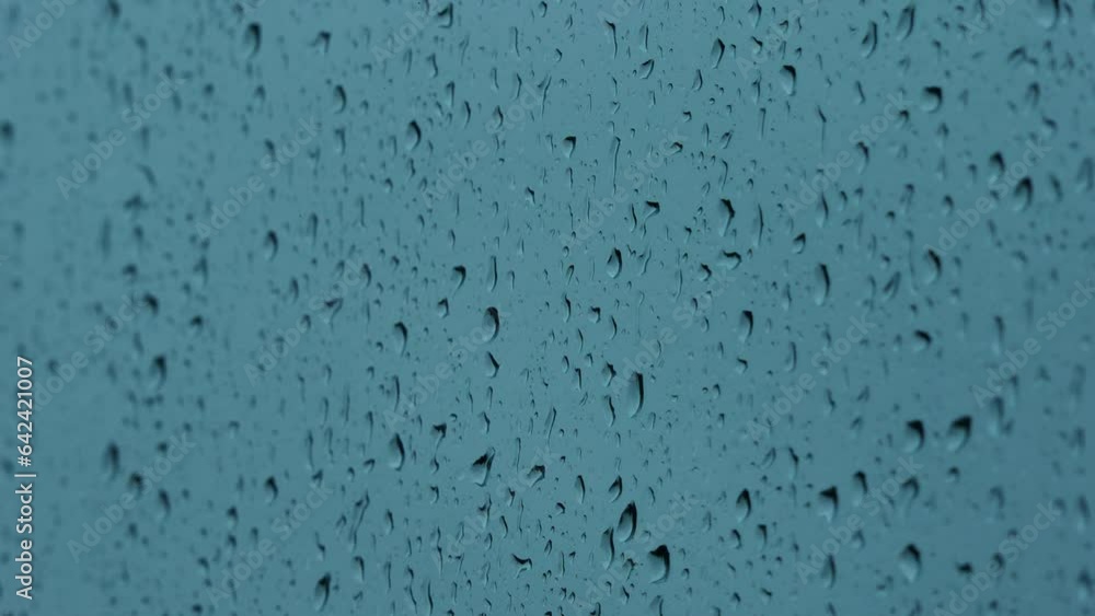 Raindrops on the window. Heavy rain on the window - heavy rain on the glass, rain green background. Droplets of water on glass background. Rain drops runnin down the window glass at rainy day Raindrops on the window. Heavy rain on the window - heavy rain on the glass, rain green background. Droplets of water on glass background. Rain drops runnin down the window glass at rainy day