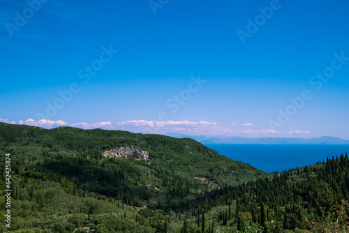 Scenic top view of the green slopes of the mountains and the sea on a clear sunny day.