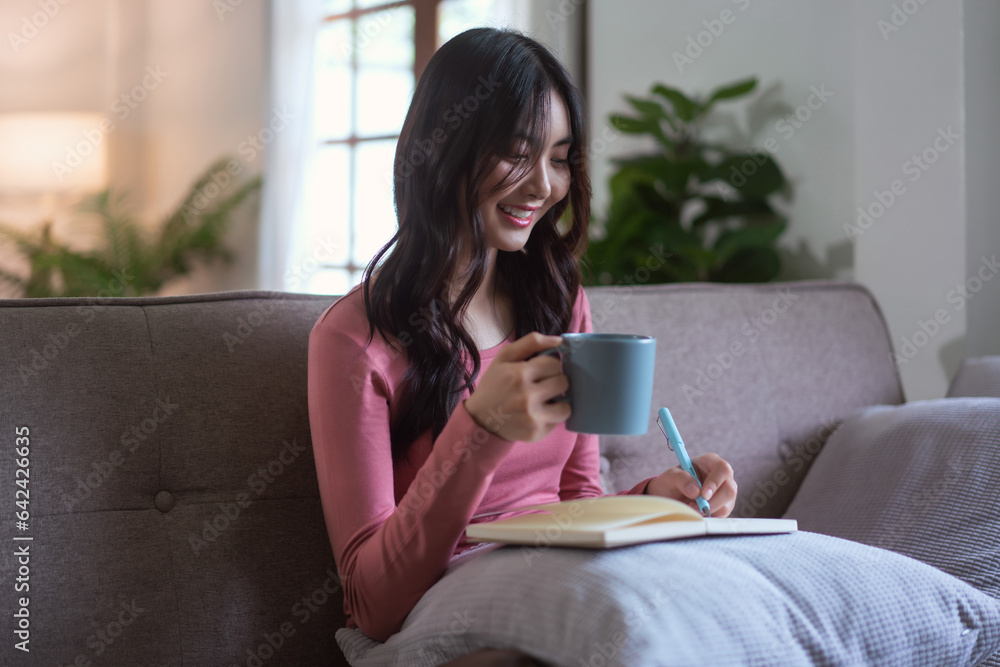 Women leisure on sofa to drinking coffee and writing notes on diary notebook in lifestyle at home Women leisure on sofa to drinking coffee and writing notes on diary notebook in lifestyle at home