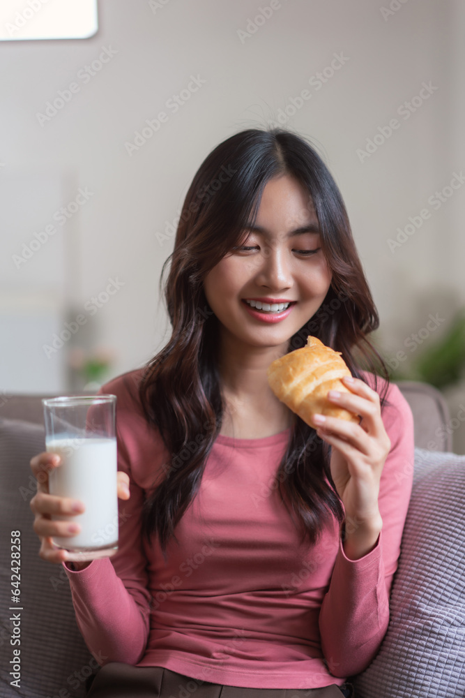 Women leisure on sofa to drinking milk and eating bread with healthy meal in lifestyle at home