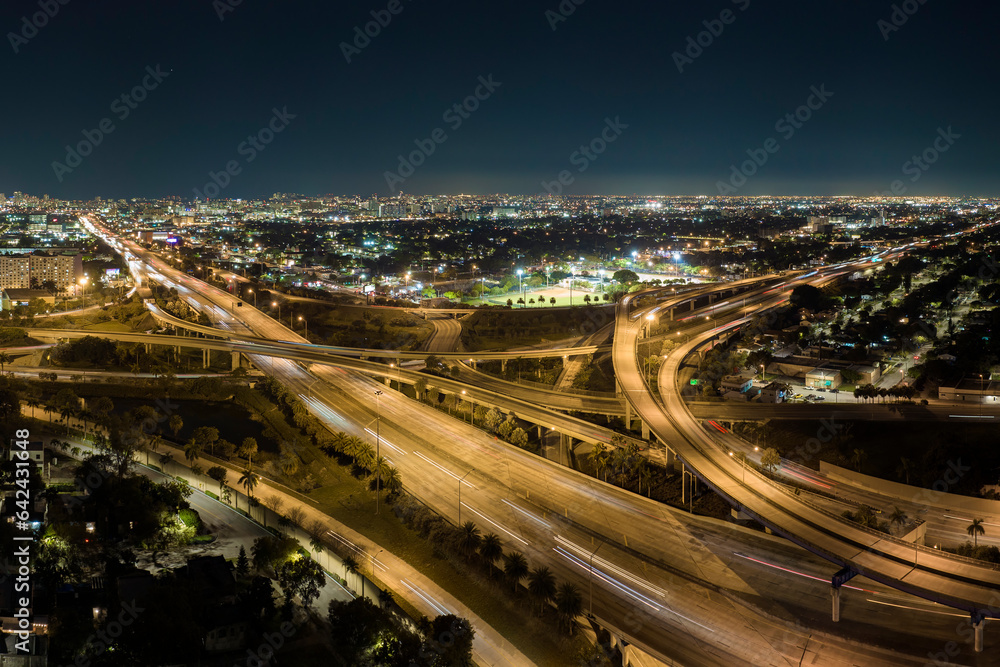 Aerial view of american freeway intersection at night with fast driving cars and trucks in Miami, Florida. View from above of USA transportation infrastructure