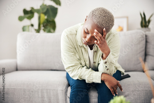 Woman, depression and headache in home for anxiety, mental health and stress of mistake, debt or crisis. Tired, sad and frustrated african person with emotional trauma, broken heart and worry on sofa