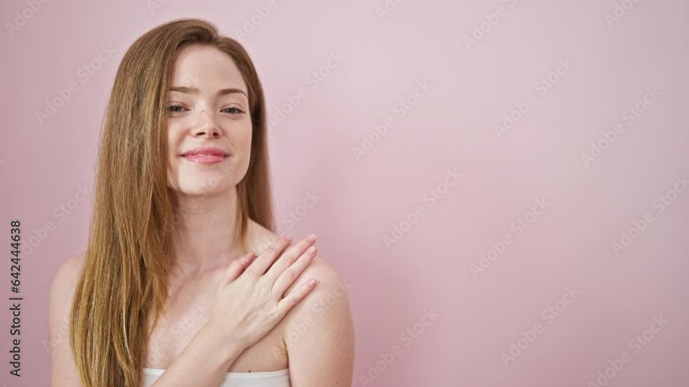Young blonde woman smiling confident touching face with hands over isolated pink background Young blonde woman smiling confident touching face with hands over isolated pink background