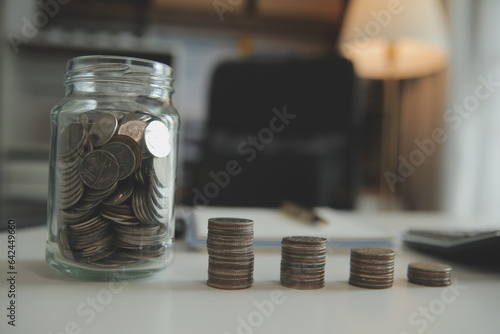 saving money and accounting concept. business man putting coin insert to jar and make acounting book for finance management to investment and saving. photo