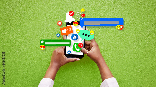 Phone, person hands and social media emojis for online network, contact or application feedback. Cellphone, closeup and user typing post, communication and like notification on green background wall photo