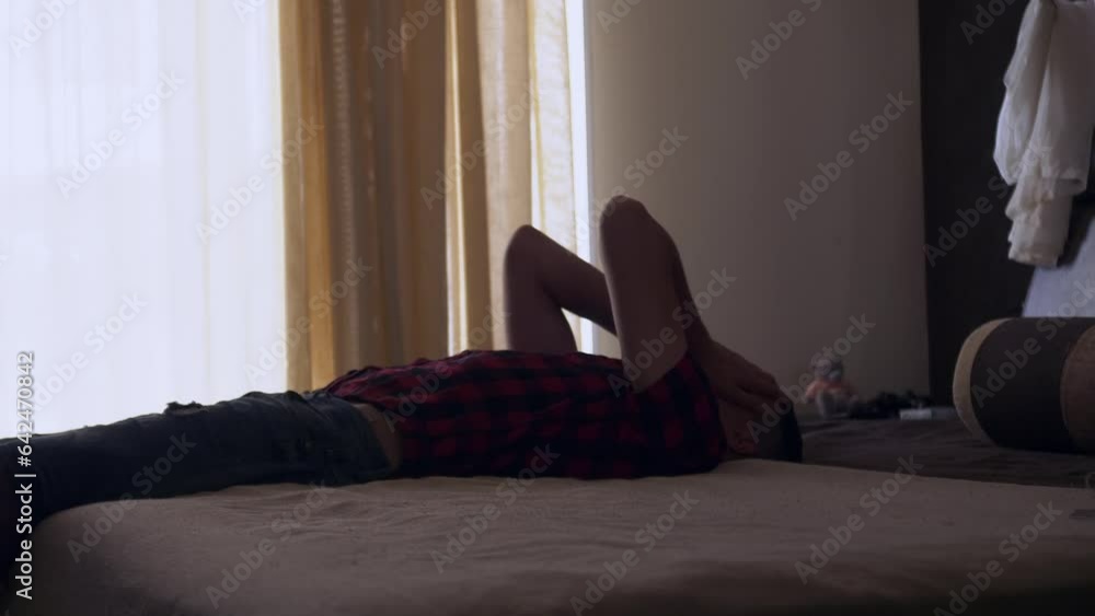 Portrait of upset millennial young man falls on a bed. Frustrated sad man thinking about something Portrait of upset millennial young man falls on a bed. Frustrated sad man thinking about something