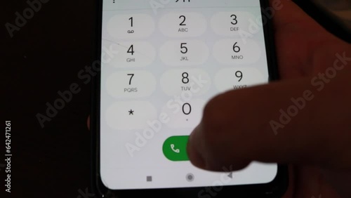 Close-up hand dialing 911 on a mobile phone in the dark to contact the police during an emergency or a crime