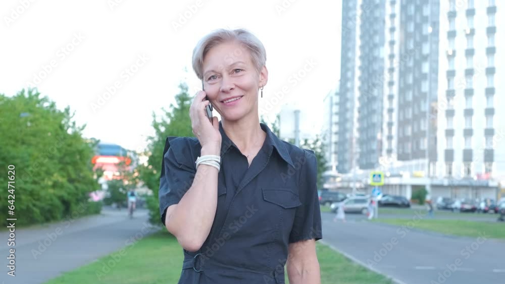 Business Woman With smartPhone Near Office. Portrait Of Beautiful senior Female In Fashion Office Clothes Talking On Phone While Standing Outdoors. Phone Communication. Business Woman With smartPhone Near Office. Portrait Of Beautiful senior Female In Fashion Office Clothes Talking On Phone While Standing Outdoors. Phone Communication.