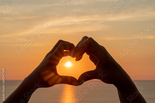 Hands heart sea sanset. Hands forming a heart shape made against the sun sky of a sunrise or sunset on a beach
