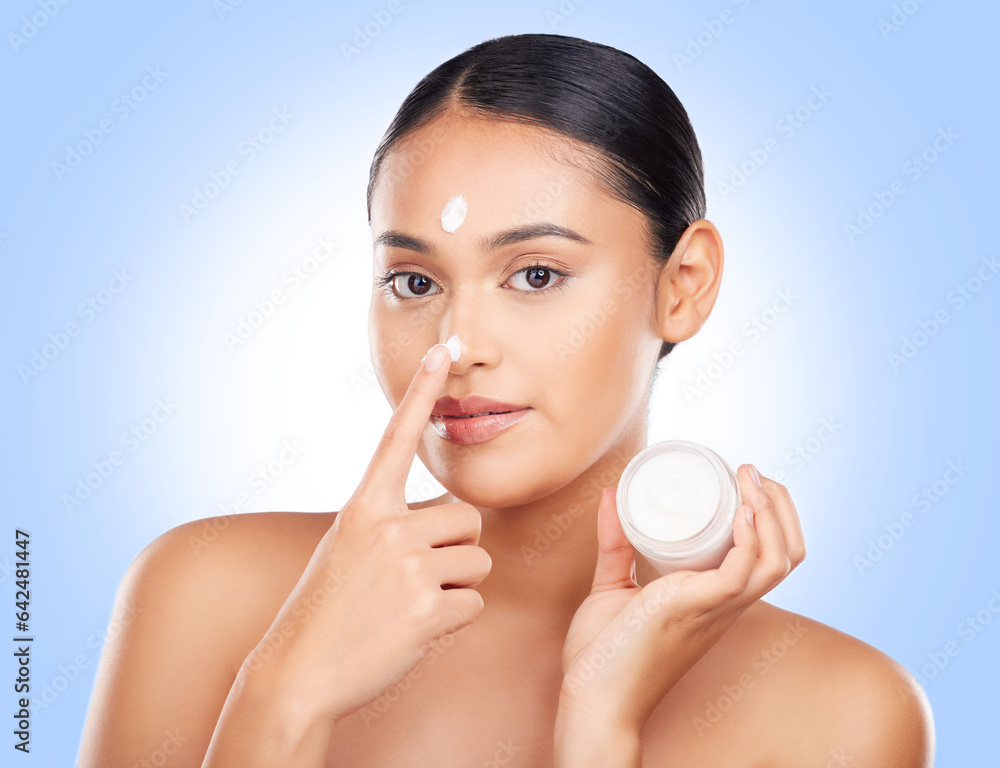 Portrait, woman and face cream container in studio for aesthetic skincare, shine and promo on blue background . Model, facial beauty and moisturizer jar of sunscreen, dermatology or cosmetics on nose