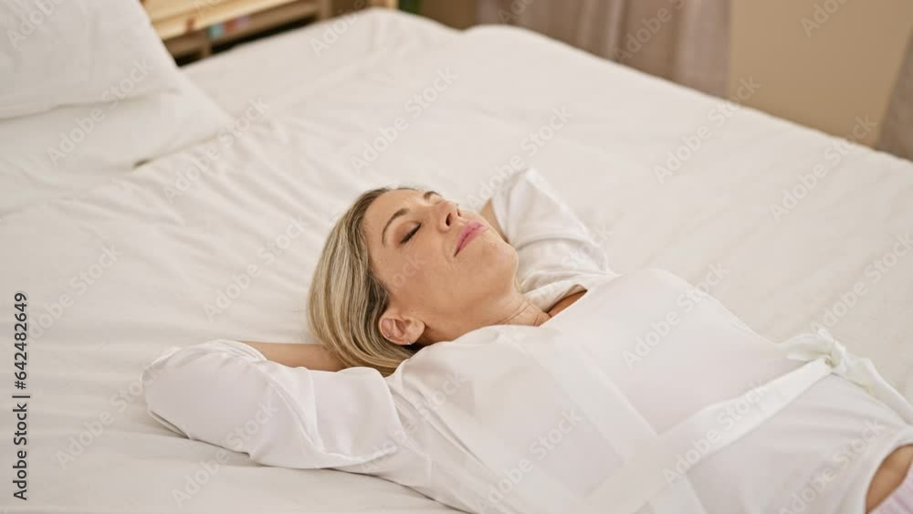 Young blonde woman lying on bed with serious expression at bedroom Young blonde woman lying on bed with serious expression at bedroom