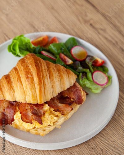 Croissant with scrambled egg, bacon and salad