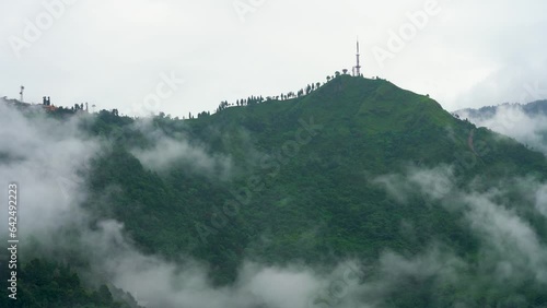panning shot showing electricity tower on hilltop in darjeeling, sikkim gantok west bengal showing lush tea gardens on green hills photo