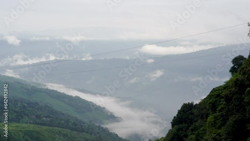 panning shot showing clouds fog rolling across hills in darjeeling gantok sikkim famous tourist place in west bengal during monsoons photo