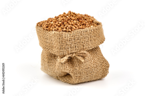 Raw buckwheat grains in rustic burlap isolated on white background.