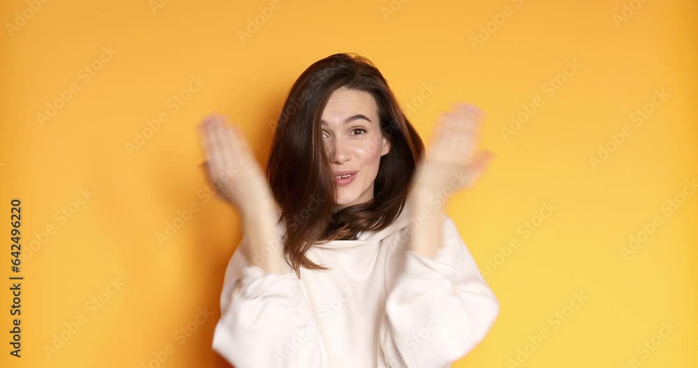 Woman wear white hoody plays hide-and-seek. She covers her face with her hands and opens smiling sweetly isolated on yellow background. Woman wear white hoody plays hide-and-seek. She covers her face with her hands and opens smiling sweetly isolated on yellow background.