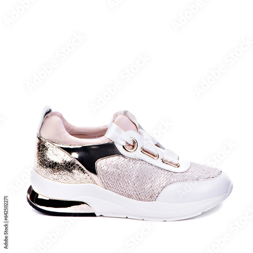 Side view of glamorous female sneaker with paillettes, white sole, metallic inserts, and white satin shoelaces isolated on a white background with copy space. Closeup. Original design. Fashion blog.
