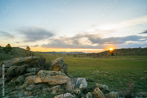 Sunset Star Burst over grean meadow of South East Wyoming Rocky Mountains Clouds and Sun Burst Golden Hour with Mossy Rock in Foreground and Background Long Exposure
