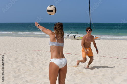 couple playing coed volleyball on the beach