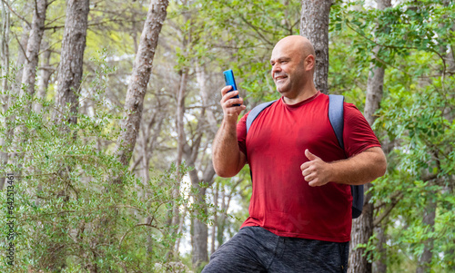 A sweaty, burly male hiker takes a selfie in the forest