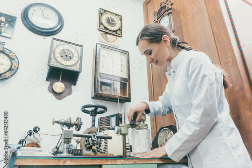 Woman watchmaker cleaning clockwork of a watch in her workshop photo