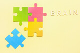 Word BRAIN with paper puzzle pieces on yellow background. Logic concept