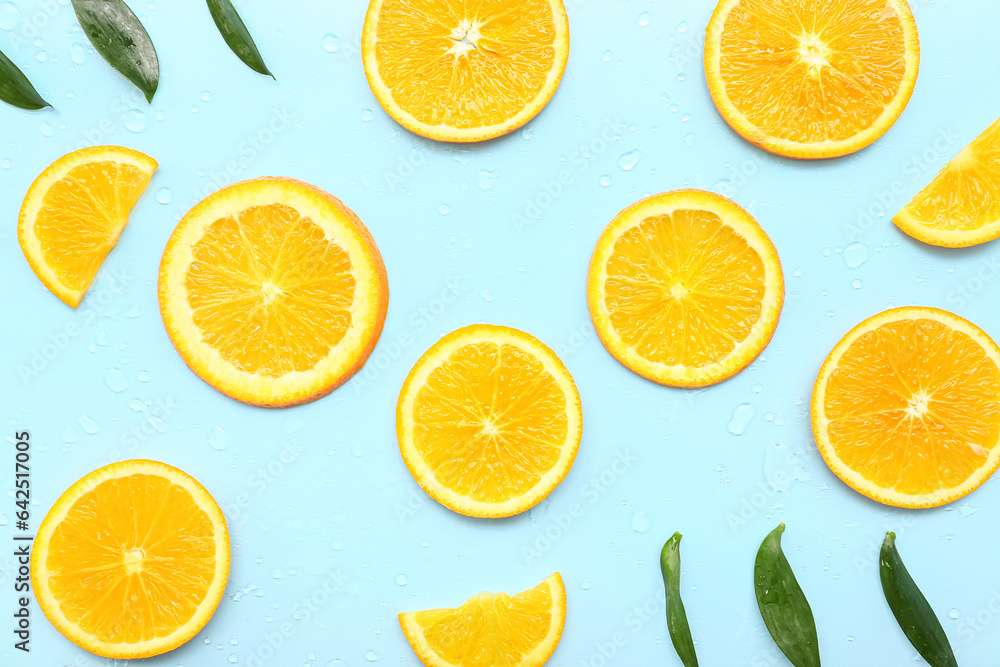 Orange slices with leaves and water drops on blue background Orange slices with leaves and water drops on blue background