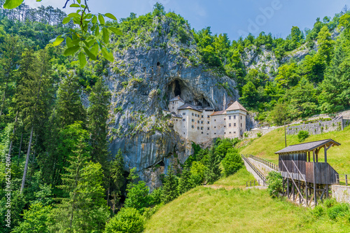 A view of the countryside and medieval castle built into the cliff face at Predjama, Slovenia in summertime photo