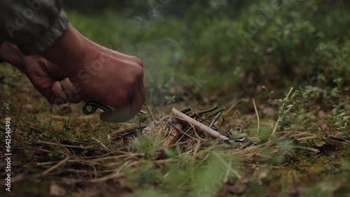 Man outdoors makeing fire by flint. Flamethrower. Survival in the wild