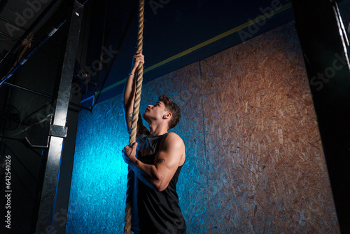 Man climbing the rope inside the gym