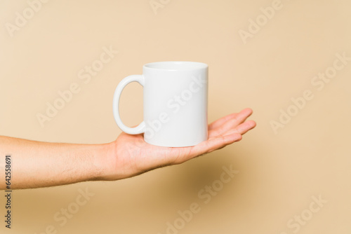 Young man holding a white mockup 11 oz mug